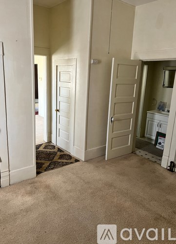 A carpeted room with a door and a cabinet.