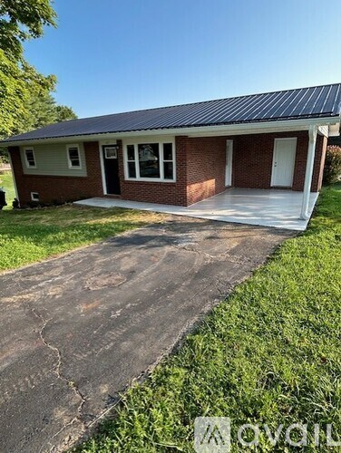 A small house with a metal roof and a concrete pathway leading to the front door.