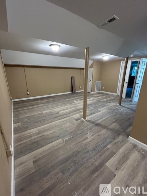 A room with wooden flooring and a wall with a window.