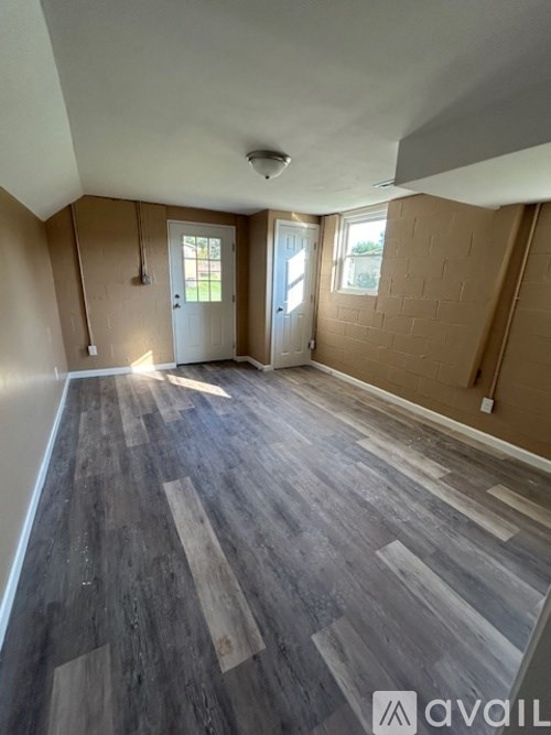 A room with wooden flooring and a door leading to a balcony.