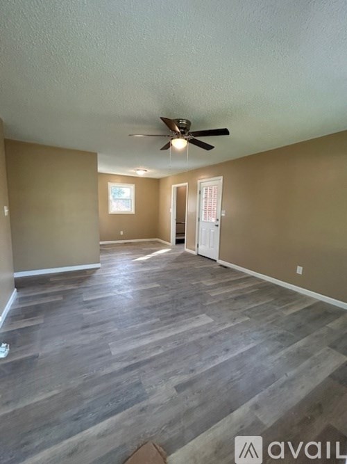 A room with a ceiling fan and wooden flooring.