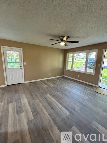 A room with a ceiling fan and wooden flooring.