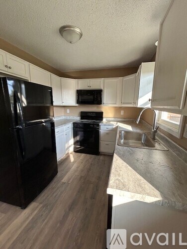 A kitchen with black appliances and white cabinets.