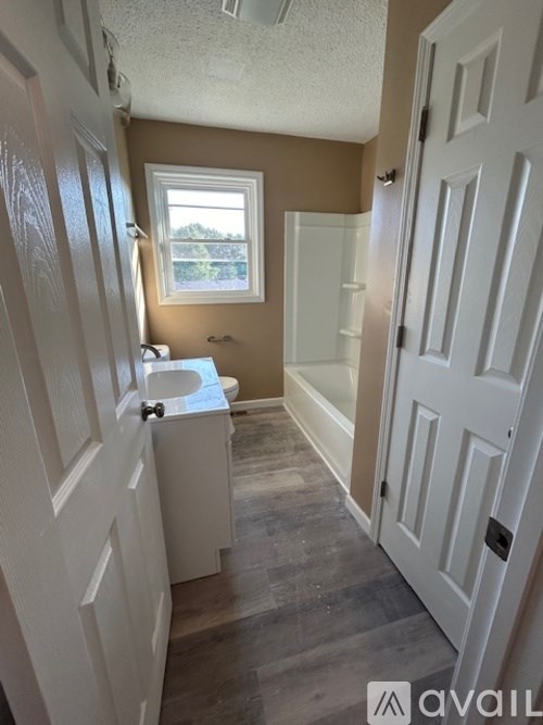 A bathroom with a toilet, sink, and window.