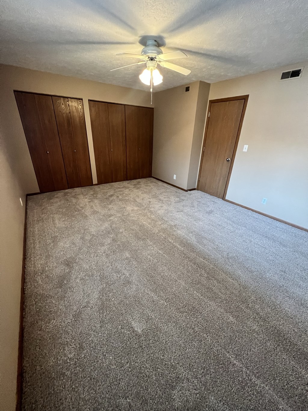 an empty room with carpet and a ceiling fan