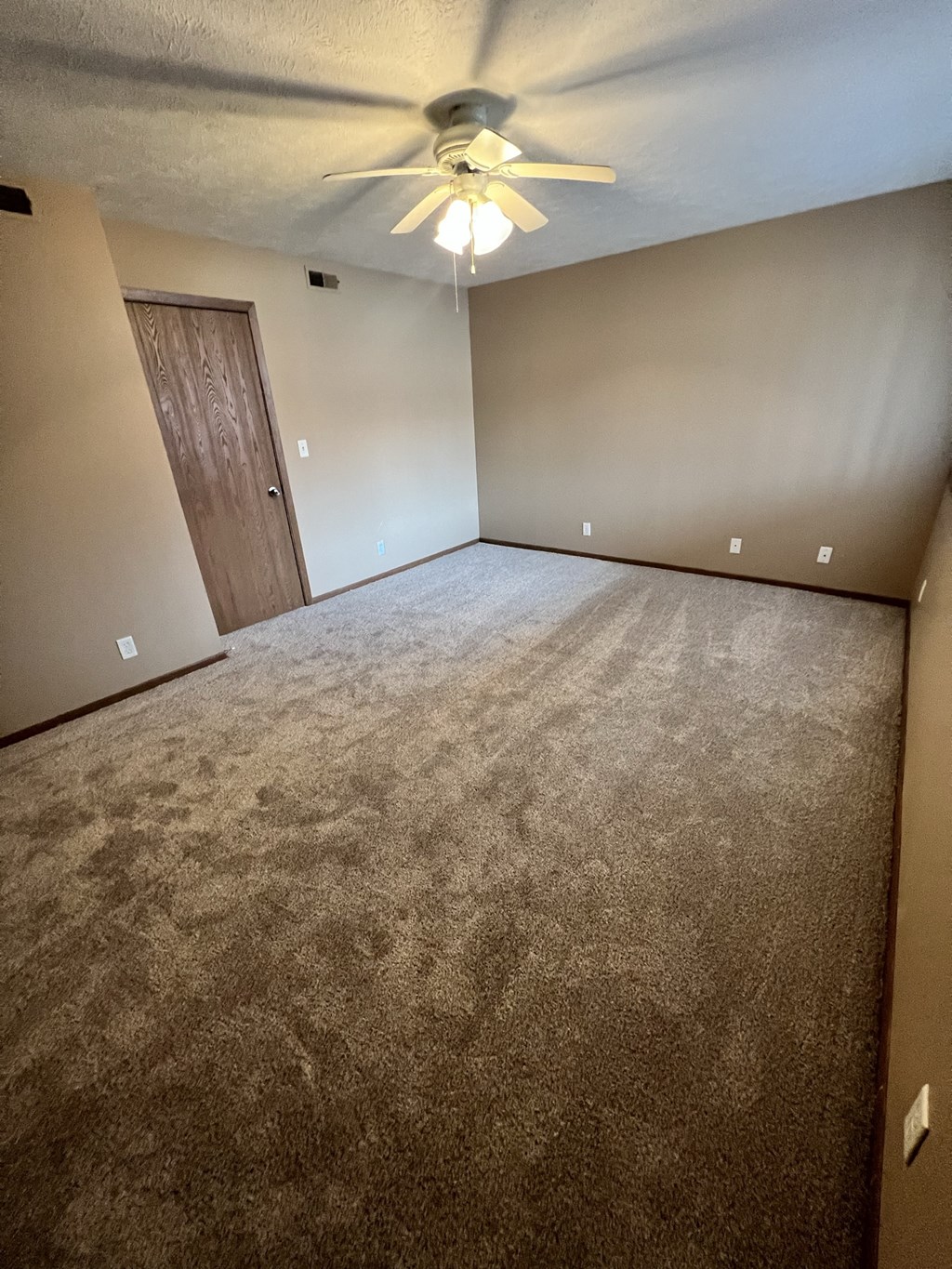 the living room of an empty house with a ceiling fan