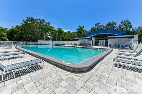 A large outdoor swimming pool with lounge chairs and a building in the background.