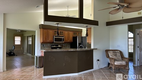 A kitchen with a brown island and a ceiling fan.