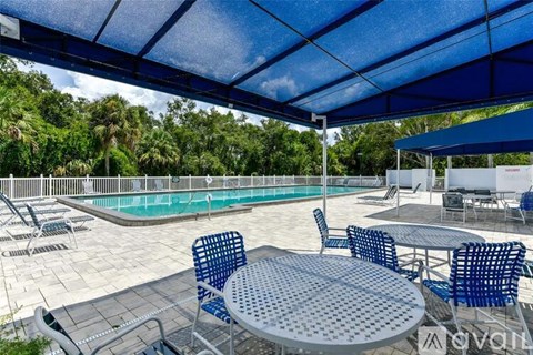 A pool area with a table and chairs under a blue canopy.