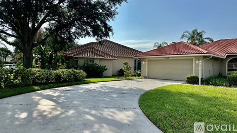 A house with a red tiled roof and a driveway in front.