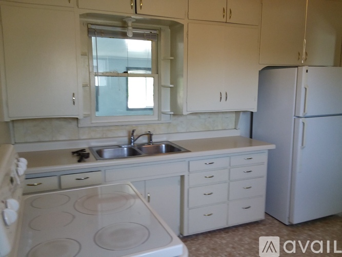 A kitchen with white cabinets and a white stove top oven.