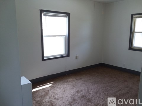 A room with a carpeted floor and two windows.