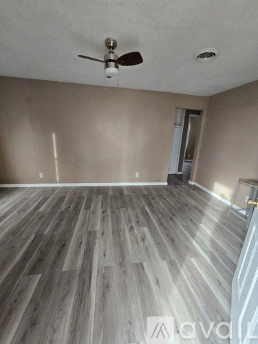 A room with wooden flooring and a ceiling fan.