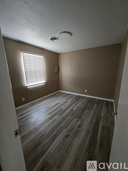A room with wooden flooring and a window with blinds.