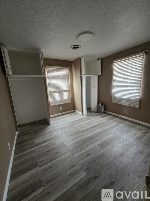 A room with wooden flooring and a window with blinds.