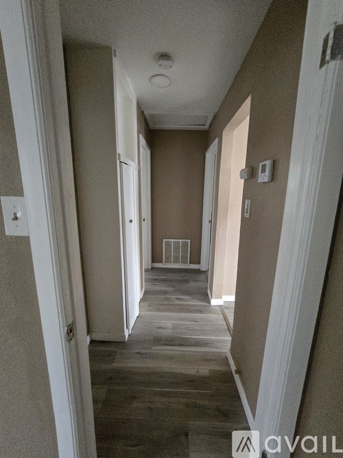 A long hallway with a light on the ceiling and a door at the end.