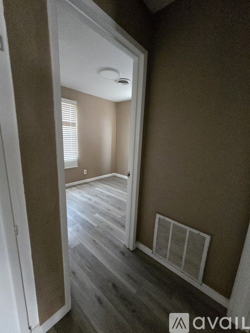 A room with a doorway leading to another room with a window.