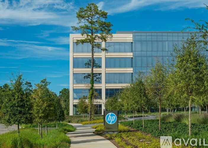 The image shows a modern building with a glass facade and a sign that reads "hp" in front of it.