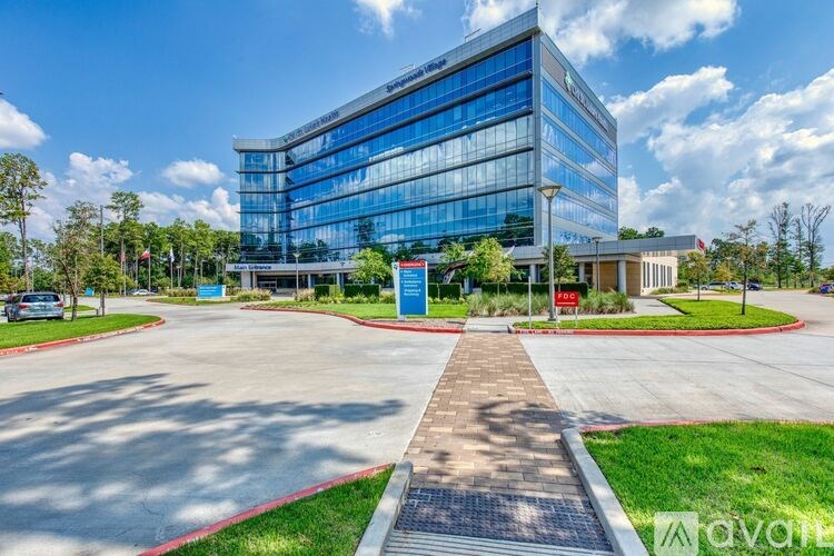 A modern glass building with a red and white sign in front.