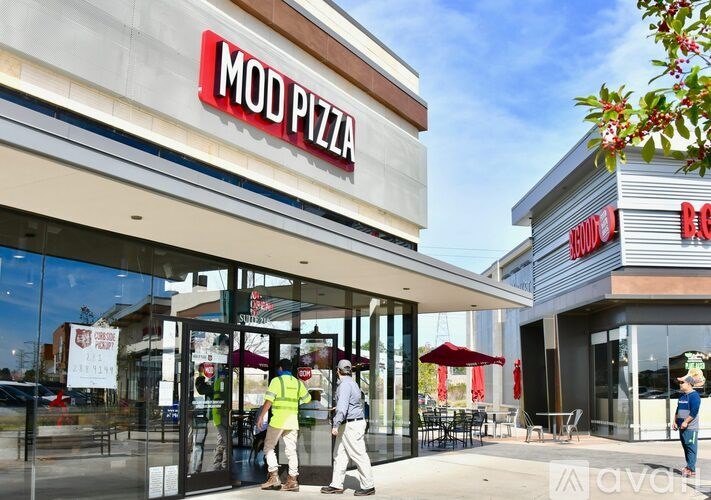 A Mod Pizza storefront with people walking by.