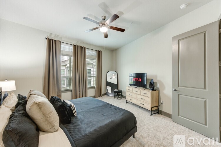 A bedroom with a bed, dresser, and ceiling fan.