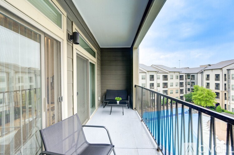 A balcony with a black chair and a small table.