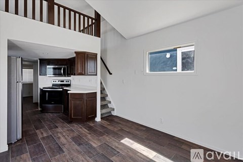 A kitchen with a refrigerator, microwave, and oven is in a house with a staircase.