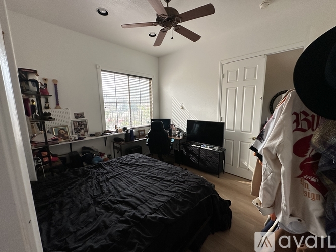 A bedroom with a black bed and a ceiling fan.