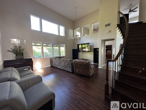 A living room with a grey couch and a wooden staircase.
