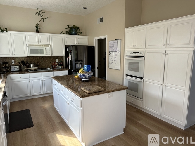 A kitchen with white cabinets and a brown countertop.
