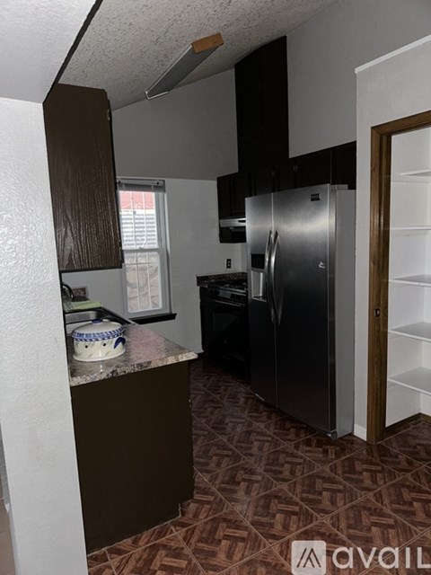 A kitchen with a refrigerator, cabinets, and a patterned floor.