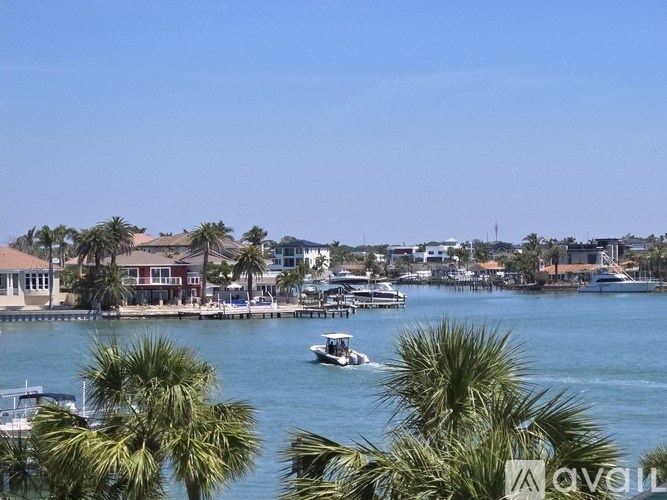 A boat is sailing on the water near some buildings and palm trees.