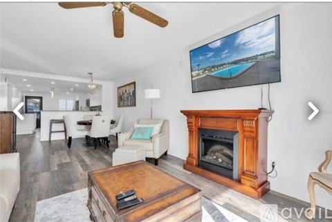 A living room with a fireplace and a television mounted above it.