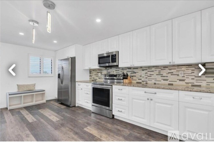 A kitchen with white cabinets and a stone backsplash.