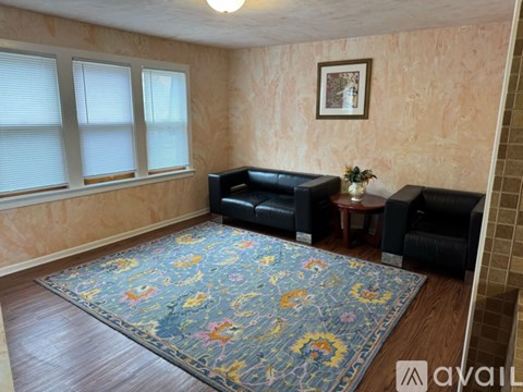 A living room with a blue floral rug and two black leather sofas.