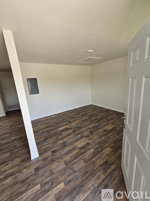 A room with wooden flooring and a white door.