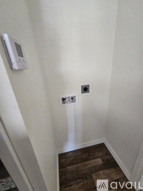 A white wall with a thermostat and a light switch.