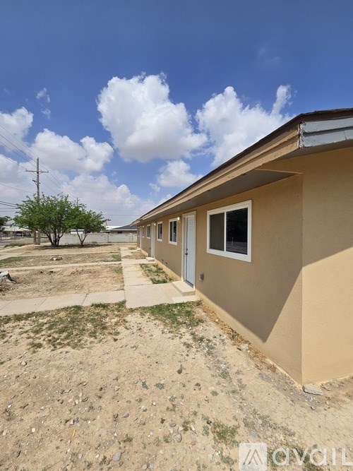 A beige house with a white door and a small tree in the yard.