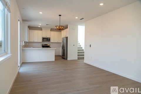A modern kitchen with white cabinets and a wooden floor.