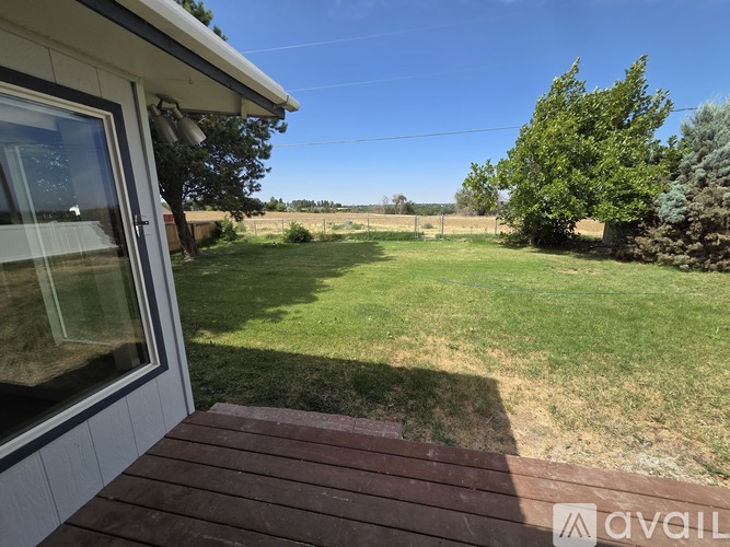 A house with a wooden deck overlooks a green yard.