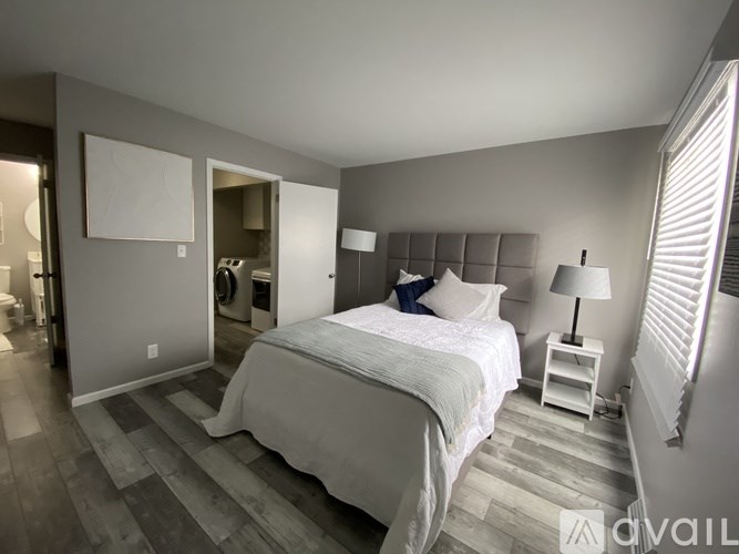 A bedroom with a large bed and a nightstand with a lamp.