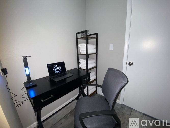 A black desk with a chair and a sign that says "Stay Home" on it.