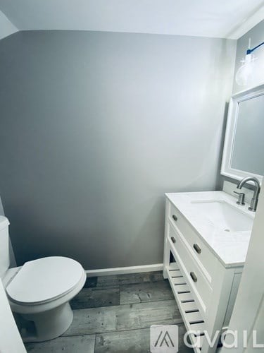 A white toilet sits next to a white sink in a small bathroom.