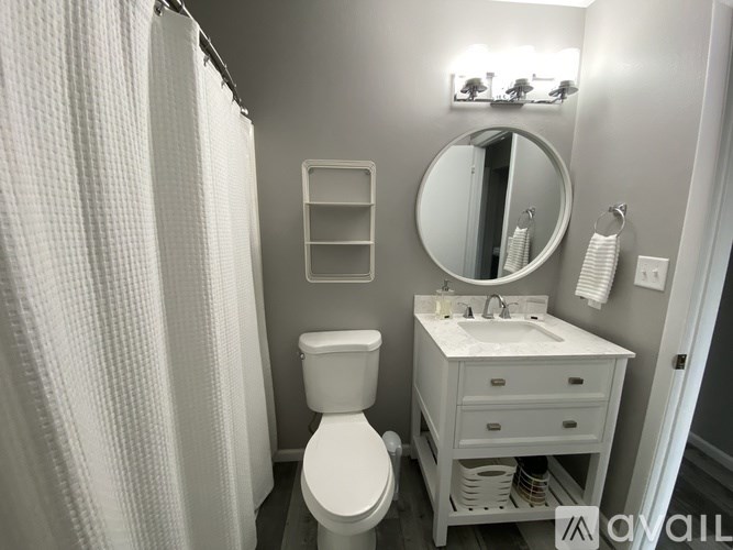 A white bathroom with a toilet, sink, and shower curtain.