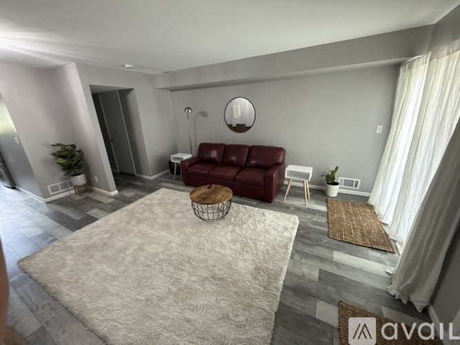 A living room with a red couch and a round mirror on the wall.