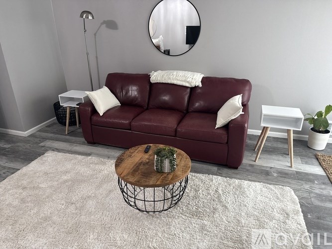 A red leather couch with a white pillow and a white throw on it.
