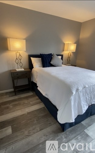 A bedroom with a bed, nightstands, and lamps.