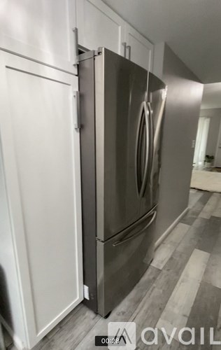 A stainless steel refrigerator with a white door is in a kitchen.