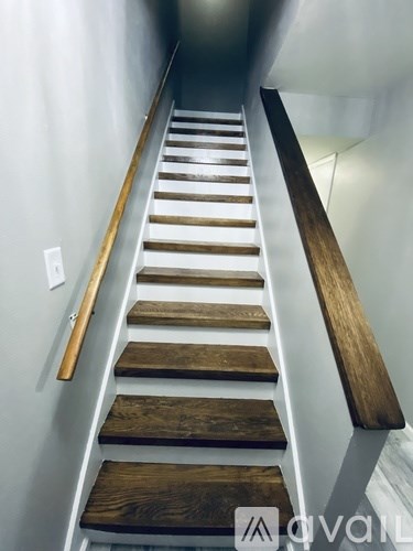 A set of wooden stairs with a metal handrail.