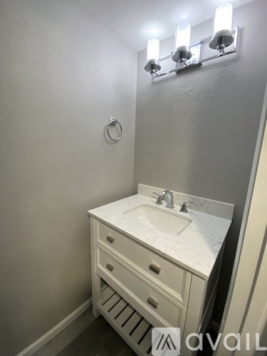 A bathroom with a sink and a light on the wall.